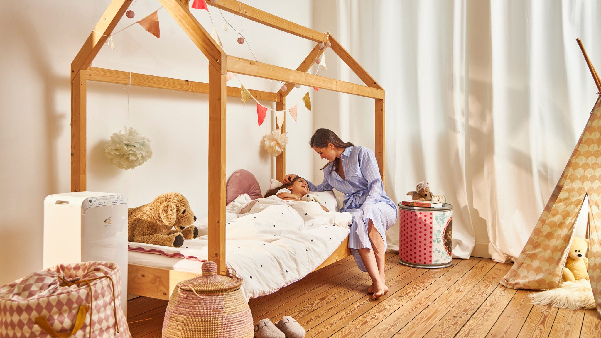 Majka ušuškava dete u krevetac u zdravom domu zahvaljujući Daikin prečistaču vazduha u dečjoj sobi