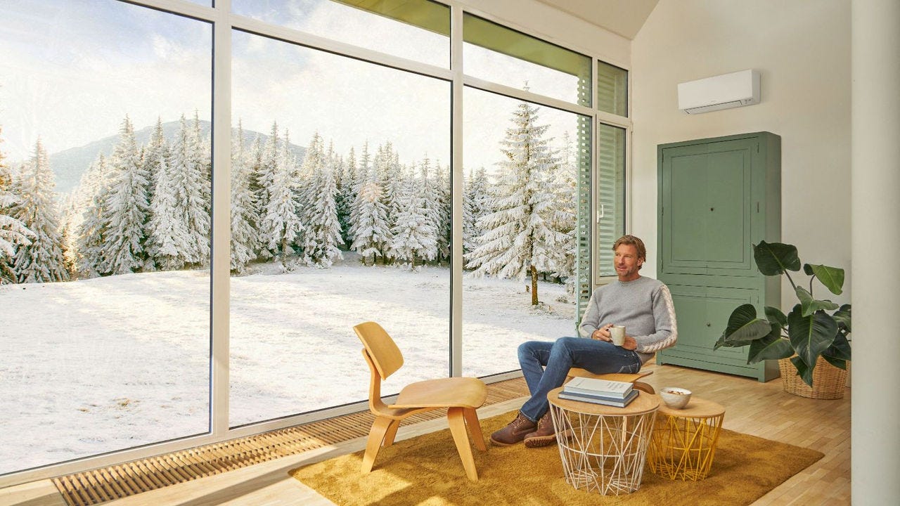 Muškarac sedi na sofi i uživa u grejanju uz klima-uređaj