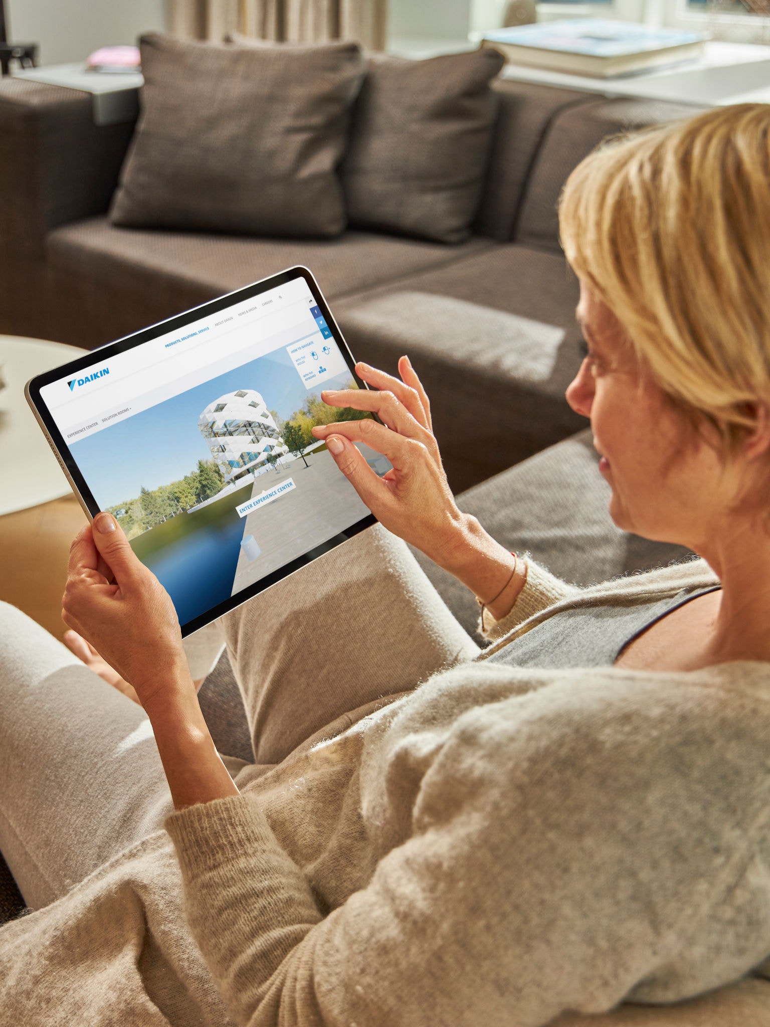 Žena sedi na sofi i na svom tabletu razgleda klima-uređaje u Virtual Experience centru