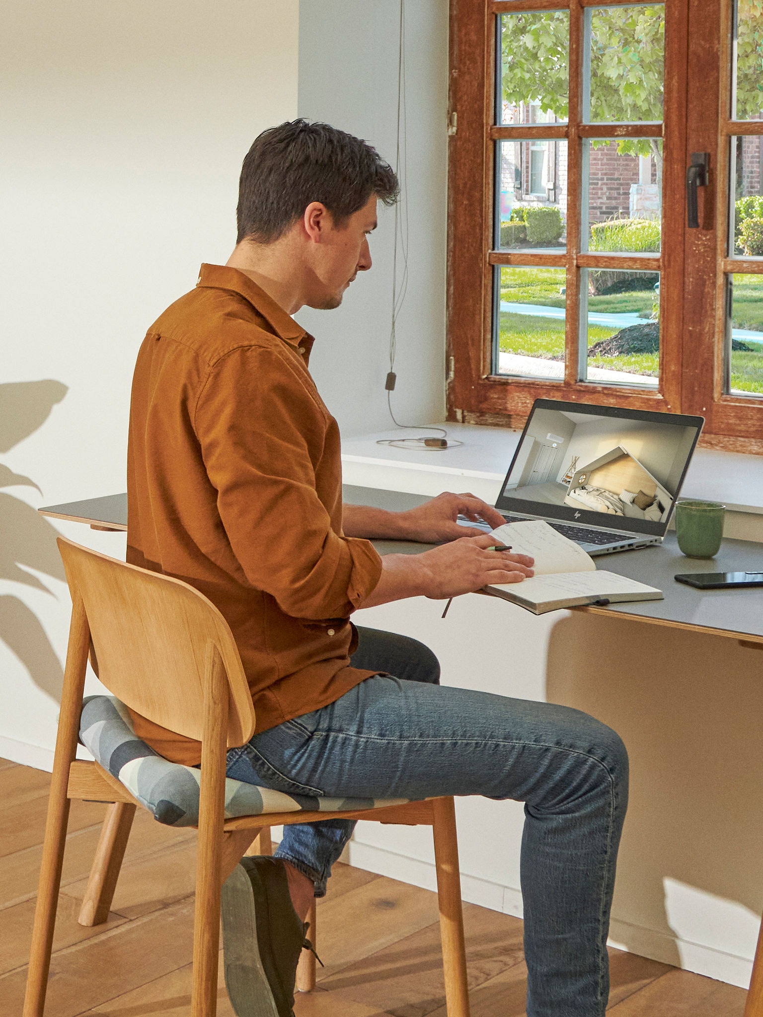 Muškarac stoji pored prozora i na svom laptopu razgleda klima-uređaje u Virtuel Experience centru