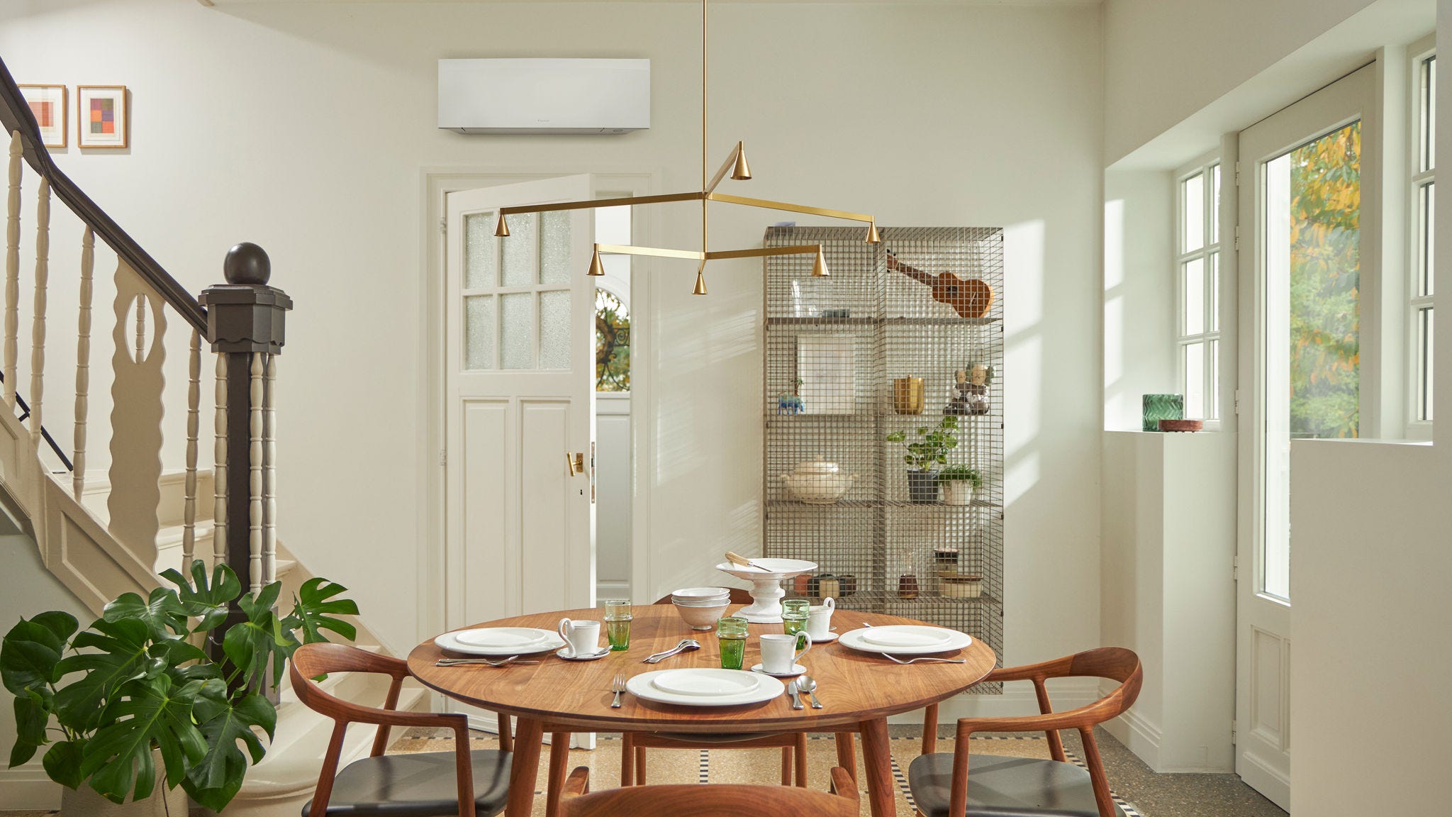 Soba sa velikim prozorom, drvenim stolom i crnim zidnim klima-uređajem