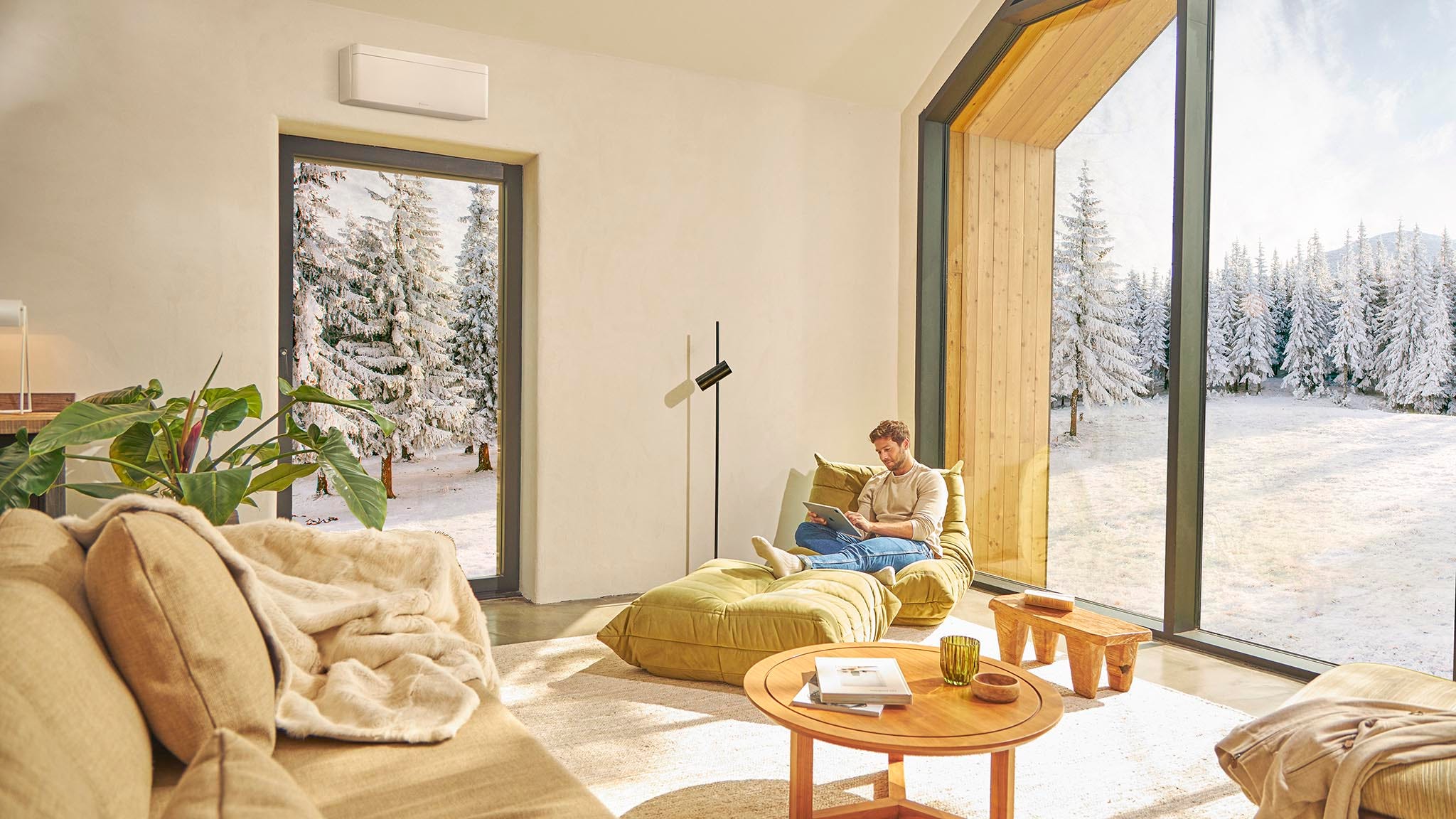 Muškarac sedi na sofi i uživa u grejanju uz klima-uređaj